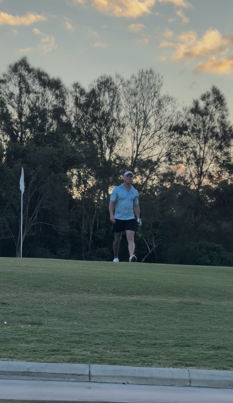 A golfer standing beside the flag at sunset